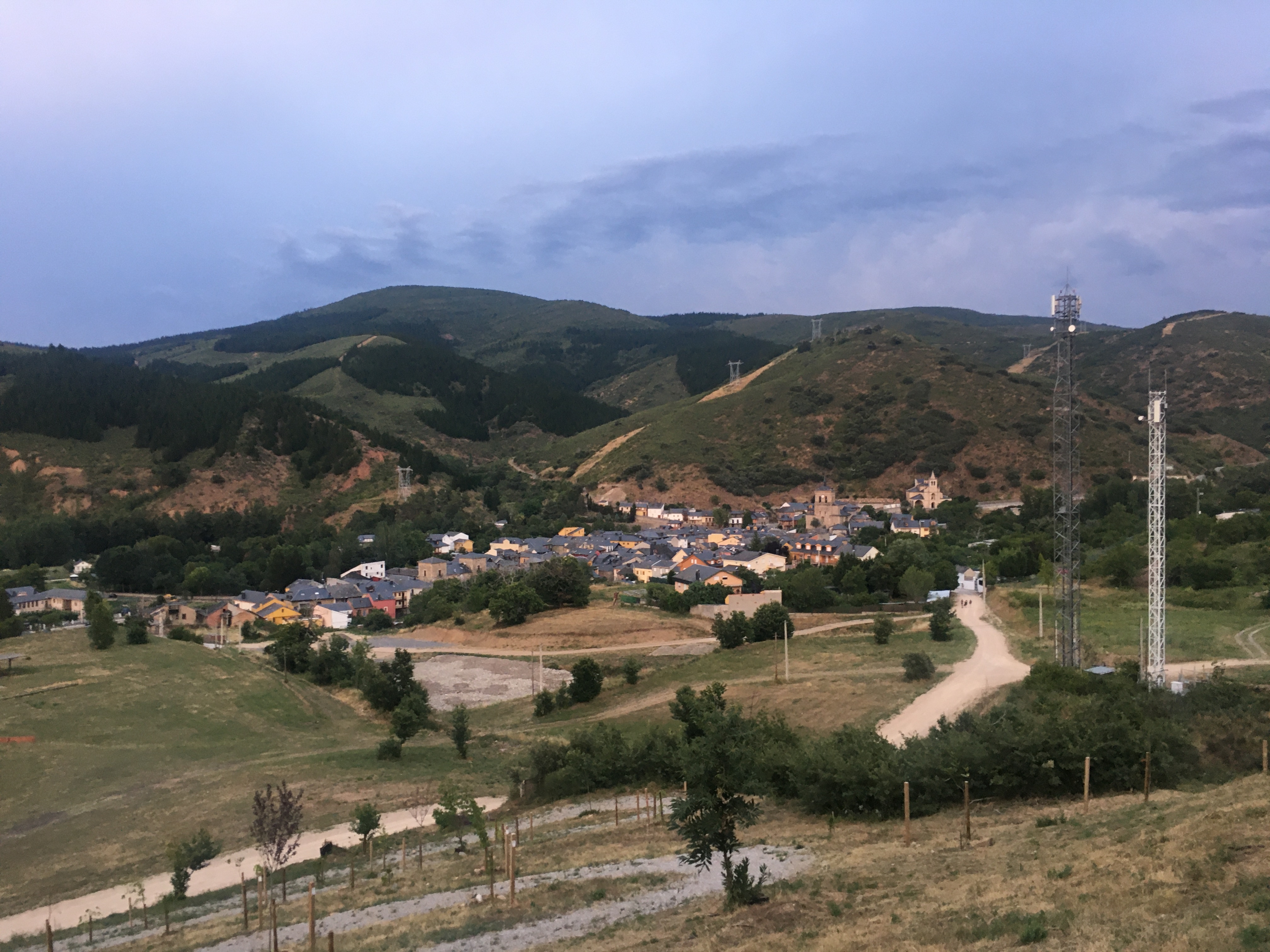 Vista desde una ladera del pueblo de Molinaseca. En el segundo plano se ve el pueblo y unas antenas de telecomunicación. En el fondo los montes leoneses.